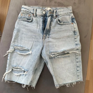 Jeansshorts  - Något längre jeansshorts i ljusblå denim med slitningar. Använda 1 gång.