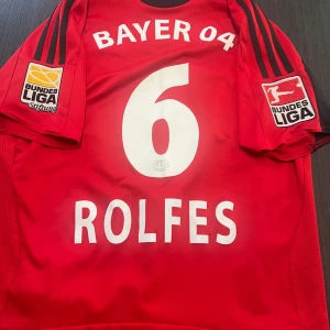 Äkta Bayer leverkusen 04 Simon Rolfes nummer 6 - Säljer min äkta Bayer leverkusen fotbollströja med ikonen Simon Rolfes! Tröjan är i storlek 13-14 år (164cm)! Den är i fint skick med med Bundesliga patches!  Hör av dig vid minsta lilla fundering! Kolla gärna in mina andra artiklar!  Fotboll fotbollströja fotbollsskor Nike Barcelona T-shirt grisch thiago alcantara Adidas football shirt Madrid Liverpool Chelsea longsleeve