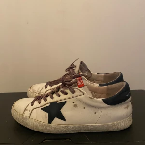 Golden Goose skor - Snygga vita sneakers med en stjärna på sidan. Storlek 42 men passar 43.Skorna har en GGDB-logga på tungan och en mörk häl. Perfekta för en avslappnad stil. Nypris: 6000+  Pris kan diskuteras 