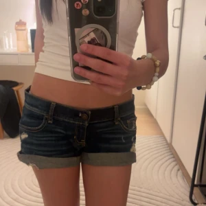 Mörkblå lågmidjade jeansshorts Hollister - Säljer ett par as snygga mörkblå Hollister jeansshorts storlek W25! Slitningarna är en del av designen💗 Skriv om du vill ha fler bilder eller har frågor❣️ Mått: Midja rakt över: 40 cm Gylf: 10 cm Lår: ca 52 cm omkrets 