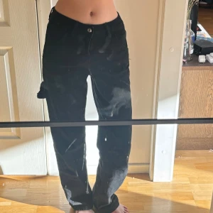 Svarta jeans med detalj  - Snygga svarta jeans med en knapp framtill. De har en rak passform och är perfekta för en stilren look. Byxorna har fickor och en klassisk design som funkar till många tillfällen.