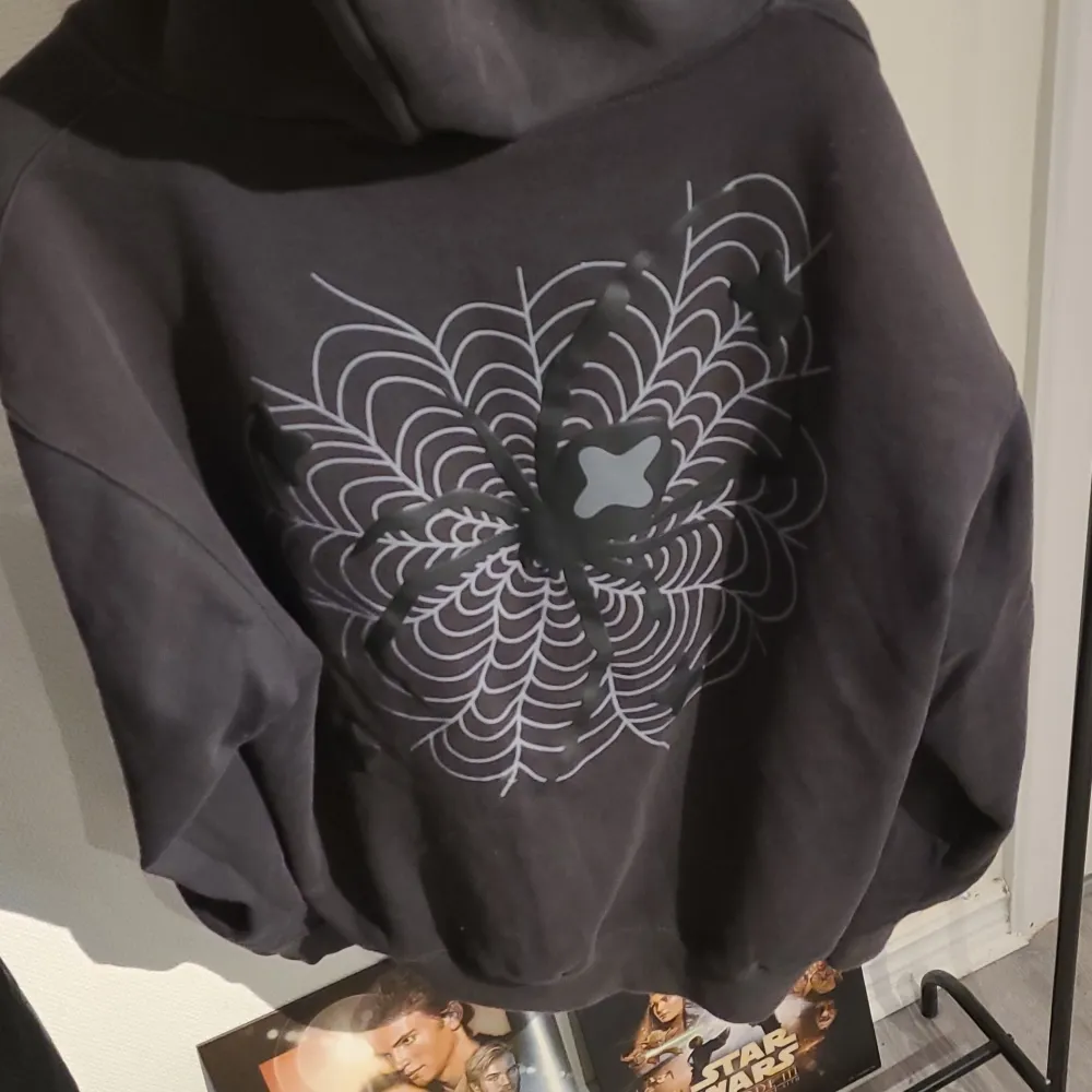 Säljer en svart hoodie från Broken Planet med dragkedja och coolt planetmotiv på bröstet. Baksidan har ett unikt mönster som ger en extra touch. Perfekt för dig som vill ha en stilren men ändå iögonfallande look.. Neuletakit & Villapaidat.
