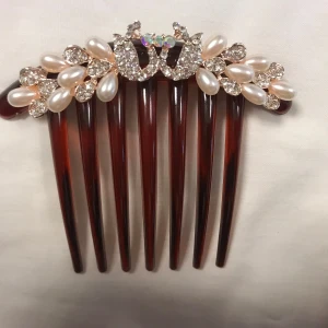 Hårkam med pärlor och strass - Elegant hårkam i brun nyans dekorerad med vita pärlor och glittrande strass. Perfekt för att ge en extra touch av glamour till din frisyr. 89kr/st , helt ny 