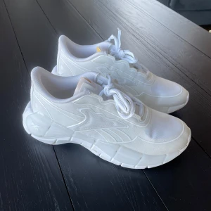 Vita sneakers från Reebok - Snygga vita sneakers från Reebok (Victoria Beckham) med en stilren design. Skorna har snörning och en bekväm sula som ger bra stöd. Perfekta för en sportig look eller en avslappnad dag på stan. 