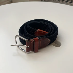 Flätat bälte från SADDLER - Flätat bälte, 85 cm. Äkta läder och fint skick. 9/10. Använt fåtal gånger. Hör av dig vid frågor eller funderingar.