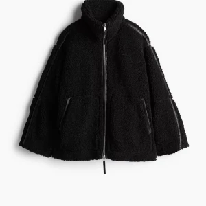 Svart teddyjacka från H&M - Mysig svart teddyjacka från H&M med dragkedja framtill. Jackan har en hög krage och två fickor med dragkedja. 