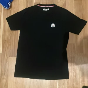 Moncler tröja KoP1a - Säljer en stilren svart t-shirt från Moncler med deras ikoniska logga på bröstet. Tröjan är som ny och är en KOp1A där av priset. Storlek är S. Skriv gärna vid minsta funderingar!