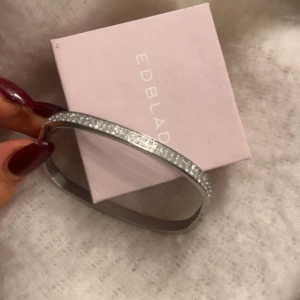 Glittrigt armband från Edblad - Snyggt och elegant armband från Edblad i silverfärg med glittrande detaljer. Två stenar har tappats men inget man ser. Kom privat för fler bilder!