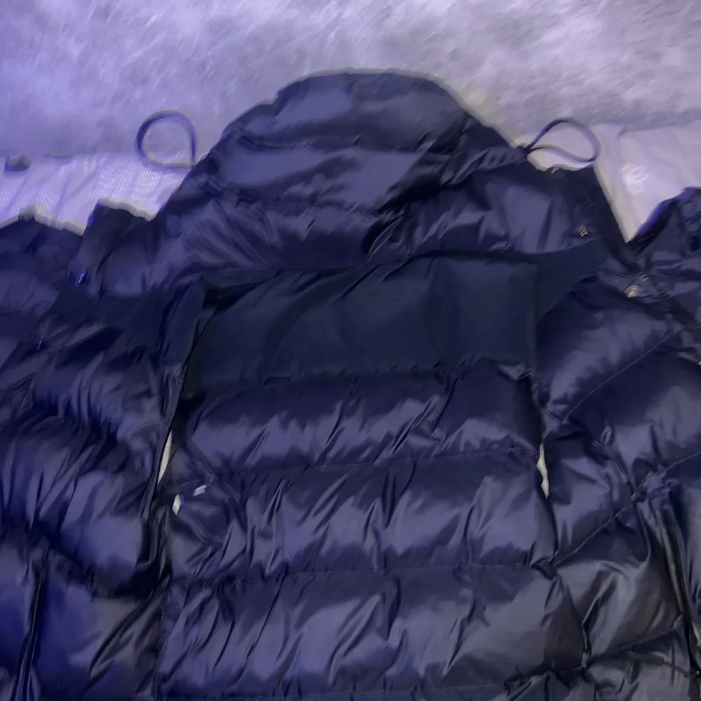 Säljer en stilren svart dunjacka från Burberry. Jackan har en klassisk rutig insida och är perfekt för kyliga dagar. Den har långa ärmar och en snygg design med Burberry-logga på ärmen. Passar perfekt för dig som vill ha både stil och komfort kan bli väst och funkar perfekt till sommaren skriv vid intresse eller om ni har frågor priset går att diskutera👍🏽. Takit.