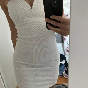 Vit bandeau klänning - Super fin vit och kort bandeu klänning med tight passform och detalj vid brösten. Brukar själv vika upp klänningen och använda som topp också!!