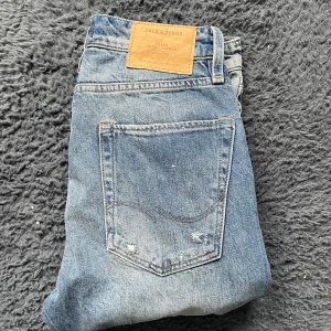  Jack & Jones jeans  - Snygga blå jeans från Jack & Jones med coola röda sidodetaljer där det står 'ORIGINALS'. Jeansen har en straight passform och är tillverkade i denim. Perfekta för en avslappnad stil med en twist.  Tyvärr kan jag inte skicka bild när jag själv bär plagget då jag för det första ofta inte kan ha storlekarna jag säljer och för det andra skulle det bli alldeles för mycket jobb när jag säljer så mycket, så jag rekommenderar att man kikar måtten på sista bilden heller googlar på modellnamnet.