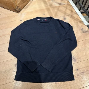 Svart t Tommy Hilfiger tröja - Säljer en stilren svart tröja från Tommy Hilfiger i en mjuk bomulls- och kashmirblandning. Tröjan har långa ärmar och en liten logotyp på bröstet. Perfekt för en klassisk look.