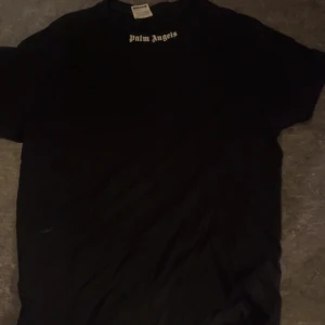 Svart t-shirt från Palm Angels - Snygg svart t-shirt från Palm Angels med deras ikoniska logga tryckt både fram och bak. Perfekt för en stilren och avslappnad look. Passar bra till jeans eller shorts för en casual stil.