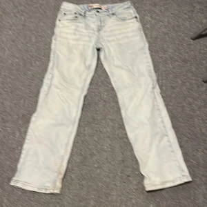Ljusblå jeans från Levi's 551 Z 10 år eller 146 - Säljer ett par ljusblå Levi's jeans med klassisk femficksdesign och rak passform. De har en traditionell Levi's läderlapp baktill och är tillverkade i denim. Perfekta för en avslappnad stil.