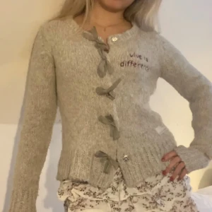 Odd Molly kofta - Grå stickad kofta från Odd Molly. Med rosetter framtill och unik design med ”hål” på sidan av ärmarna