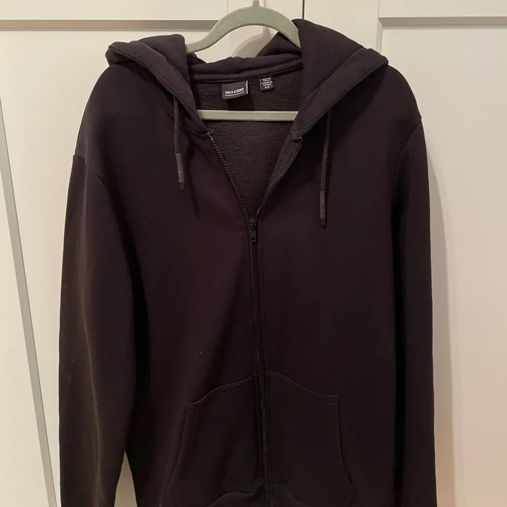 Säljer en svart hoodie från Only & Sons med dragkedja och huva. Den har långa ärmar och snörning vid huvan. Perfekt för en stilren look. Helt oanvänd! Bara höra av sig vid frågor!. Neuletakit & Villapaidat.