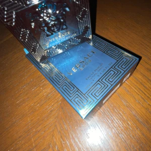 Versace Eros Eau de Parfum - Säljer en flaska Versace Eros Eau de Parfum, 100 ml. Flaskan har en elegant design med ett blått och guldigt mönster och ett ikoniskt Medusa-huvud. Perfekt för den som vill ha en doft med karaktär och stil.Helt ny!