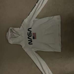 Vit NASA hoodie från H&M - Säljer en vit hoodie från H&M med NASA-logga och amerikansk flagga på framsidan. Texten 'EXPLORERS WANTED' finns på ärmen. Perfekt för rymdentusiaster! 🪐