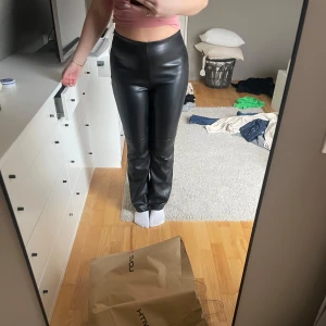 Svarta skinnbyxor från Stockh LM Studio - Snygga svarta skinnbyxor från Stockh LM Studio med hög midja och tight passform. Byxorna har en stilren design med dragkedja och fickor baktill. Perfekta för en trendig look.