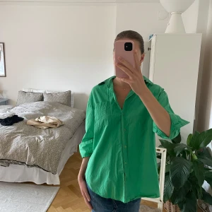 Grön skjorta  - Säljer en grön skjorta med klassisk krage och knappar framtill. Skjortan har lång ärm som enkelt kan vikas upp för en mer avslappnad look. Perfekt till jeans eller kjol för en färgstark outfit.