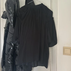 Svart blus - Säljer en svart blus med vida, luftiga ärmar. Blusen har en lös passform och är gjord i ett tunt, flowy material som ger en snygg siluett. Perfekt för dig som gillar en stilren och trendig look. 💌Köparen står för frakten!