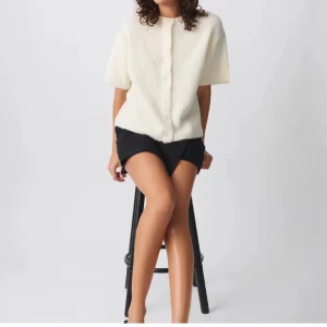 Vit stickad kofta med kort ärm från Gina Tricot - Säljer en söt vit stickad kofta från Gina Tricot med korta ärmar och rund hals. Koftan har knappar framtill. Enkel och stilren design som passar till mycket.