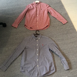 Rutig skjorta från Ralph Lauren L - Två klassiska rutiga skjortor från Ralph Lauren i storlek 14-16 år En är röd och vit, den andra blå och vit. Båda har button-down krage, långa ärmar och knappar.otroligt stilrena en för 300 två för 600