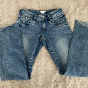 Blå jeans - Snygga blå jeans från Gina Tricot i klassisk tvätt med lätt slitna detaljer och råa benslut. Modellen har fem fickor och normal passform. Perfekta till sneakers och hoodie för en chill look. Liknar ltb