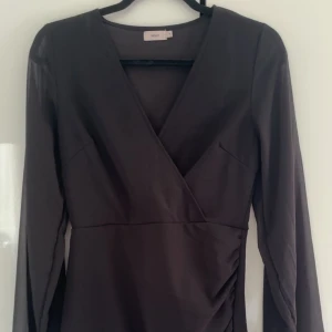 Svart omlottklänning med lång ärm från Nelly - Säljer denna svarta klänning från Nelly i storlek S. Den är använd 1 gång💞