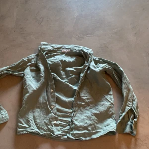 Ljusgrön linneskjorta från M. Ferrari - Säljer en ljusgrön skjorta i linne från M. Ferrari, tillverkad i Italien. Skjortan har lång ärm och klassisk krage med knappar framtill. Perfekt för en avslappnad och stilren look.