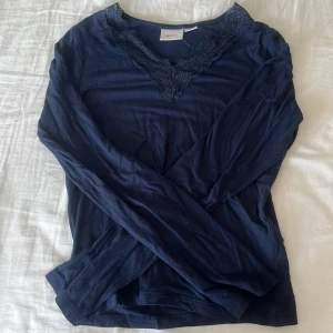 Mörkblå långärmad topp med spets - Mörkblå långärmad topp från Gina Tricot med v-ringning och snygg spetsdetalj runt halsen. Tunn och mjuk i bomullsmix, perfekt till jeans eller kjol. Storlek 146-152