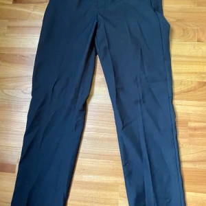 Svarta kostymbyxor från H&M slim fit - Svarta kostymbyxor från H&M i slim fit-modell. Byxorna har en klassisk rak design med justerbar midja och är tillverkade i ett mjukt tyg som ger en dressad look. Perfekta för dig som gillar stilrena och enkla plagg. Strl 164