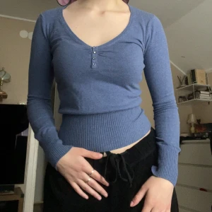 Blå ribbad tröja från Cubus - Säljer en blå långärmad tröja från Cubus med v-ringning och tre knappar framtill. Tröjan har ribbad midja och ärmar vilket ger en snygg passform. Perfekt till jeans eller kjol! Står M, men passar även som S. En av stenarna är borta, se bild 5.