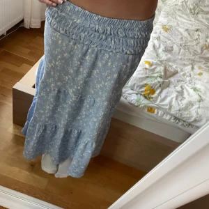 Blå blomming långkjol  - Säljer denna super söta blåa långkjol med små vita blommor på då den är lite kort. Super skön med stretchiga midja och väldigt luftig. Den passar jättebra nu till sommaren! 💗 skriv för fler bilder pris kan diskuteras 💗