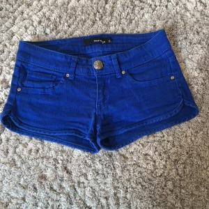 Blå jeansshorts från Taily Weijl  - Snygga blå jeansshorts med klassisk femficksdesign och knappstängning framtill. Modellen är kort och har låg midja, perfekt för varma dagar. Passar dig som gillar en enkel och stilren look.