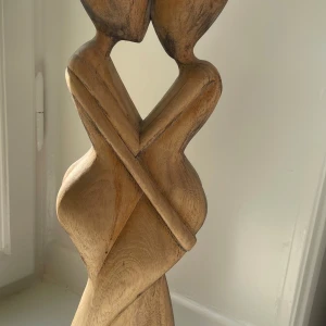 Träskulptur föreställande omfamnande par - Unik handgjord träskulptur som föreställer två personer i en kärleksfull omfamning. Skulpturen har mjuka, organiska former och är tillverkad i ljust trä med naturlig ådring. Perfekt som dekorativ inredningsdetalj.