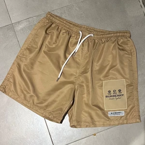 Badshorts burberry  - Beige badshorts från Burberry. Storlek L. Oanvända och således helt nya.