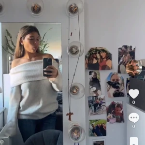 Offshoulder vit stickad tröja - Säljer en vit stickad offshoulder-tröja med bred krage. Tröjan har lång ärm och en avslappnad passform, perfekt för en trendig och mysig look.
