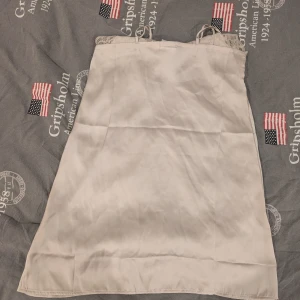 Mörkblå och Champagnefärgad pyjamas spetsklänning från H&M - Säljer en champagnefärgad kortklänning från H&M i satinliknande material med vacker spetsdetalj upptill. Klänningen är ärmlös och har smala axelband. Säljer även en mörk blå kortklänning från H&M med tunna axelband och vacker spetsdetalj upptill. Klänningen är i ett mjukt, glansigt material som ger en elegant känsla. Perfekt för dig som gillar en stilren och enkel look.