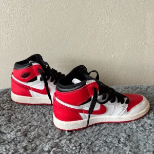 Nike Air Jordan 1 Chicago sneakers - Säljer ett par ikoniska Nike Air Jordan 1 Chicago sneakers i rött, vitt och svart skinn. Klassisk high-top siluett med svart snörning, röd yttersula och den välkända swoosh-loggan på sidorna. Perfekta för dig som vill sticka ut med en tidlös streetstyle. Stl 31 nypris 899kr från footlocker och mitt pris endast 199kr