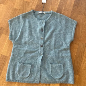 Grå stickad kofta från Yaya - Mysig grå stickad kofta från Yaya med korta ärmar och rund hals. Koftan har knäppning framtill med fyra knappar och två fickor framtill. Perfekt för lager-på-lager och enkel att matcha med olika outfits. Defekt förekommer tråden på ena fickan har börjat lossna. 