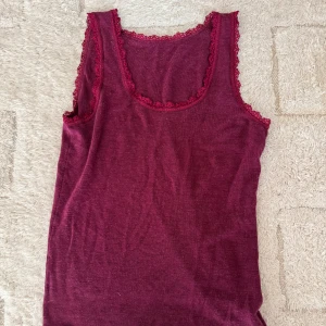 Vintage vinröd linnetopp med spetskant - Säljer en vintage vinröd linnetopp med fina spetsdetaljer runt halsringning och ärmhål. 