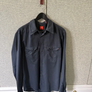 Mörkblå  skjorta från Hugo Boss - Snygg mörkblå skjorta från Hugo Boss med klassisk krage och två bröstfickor med knappar. Perfekt för dig som vill ha en stilren och enkel look. Skjortan har långa ärmar och är tillverkad i ett mjukt material.