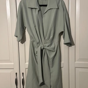 Ljusgrön omlottklänning från ASOS - Snygg ljusgrön kortklänning från ASOS DESIGN med knyt i midjan och krage. Använd 1 gång, så absolut nyskick.