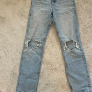 Ljusblå ripped jeans från Zara - Säljer ett par ljusblå jeans från Zara med raka ben och stora slitningar över knäna. Klassisk femficksmodell i denim. 