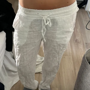 Chelsea Linnebyxor - Säljer ett par vita linnebyxor med resår och snörning i midjan. Byxorna har en avslappnad passform och sidfickor, perfekta för varma dagar. Lätta och luftiga med klassisk look. Från Chelsea! Köpt för ca 500kr? Säljer för 200kr!🥰 skulle säga att dme är i väldigt bra skick men väljer att sätta bra skick då dem används flitigt ❤️ jag är 165-166 och dem sitter bra och är i strl XXS