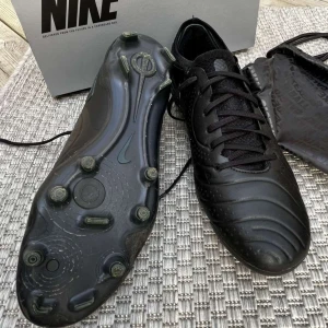 Svarta fotbollsskor Nike Tiempo - Säljer ett par helsvarta Nike Tiempo Elite fotbollsskor med klassisk design och diskret Nike-logga på sidan. Skorna har snörning, låg profil och mönstrad ovandel i syntetmaterial. Perfekta för spel på alla planer! Har använts fåtal träningar och är i bra skick 9/10! Storlek 44/uk 10 