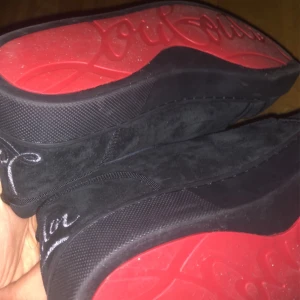 Svarta Louboutin sneakers med röd sula - Kom med prisförslag Säljer ett par svarta sneakers från Louboutin i mocka med ikonisk röd sula och broderad logga på hälen. Skorna har snörning och en stilren, rund tå. Perfekta för dig som vill sticka ut med lyxig streetstyle.