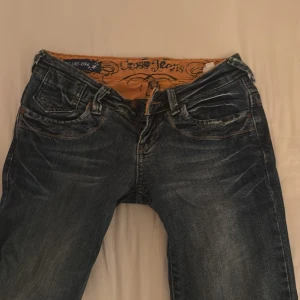 Blå bootcut jeans från Cross Jeans - Snygga blå bootcut jeans från Cross Jeans med slitningar och coola detaljer på bakfickorna. Jeansen är väldigt lågmidjade och var mina favorit jeans tills jag precis växt ur dem skriv för frågor eller liknade 