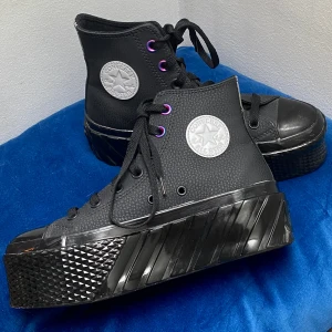 Converse All Star svarta platforms - Oanvända svarta Converse Chunk Taylor platåskor med rejäl platåsula i läder och cool struktur. Skorna har lila detaljer vid snörningen, rund tå och klassisk logga på sidan😄😄😄nypris 1019 kr 